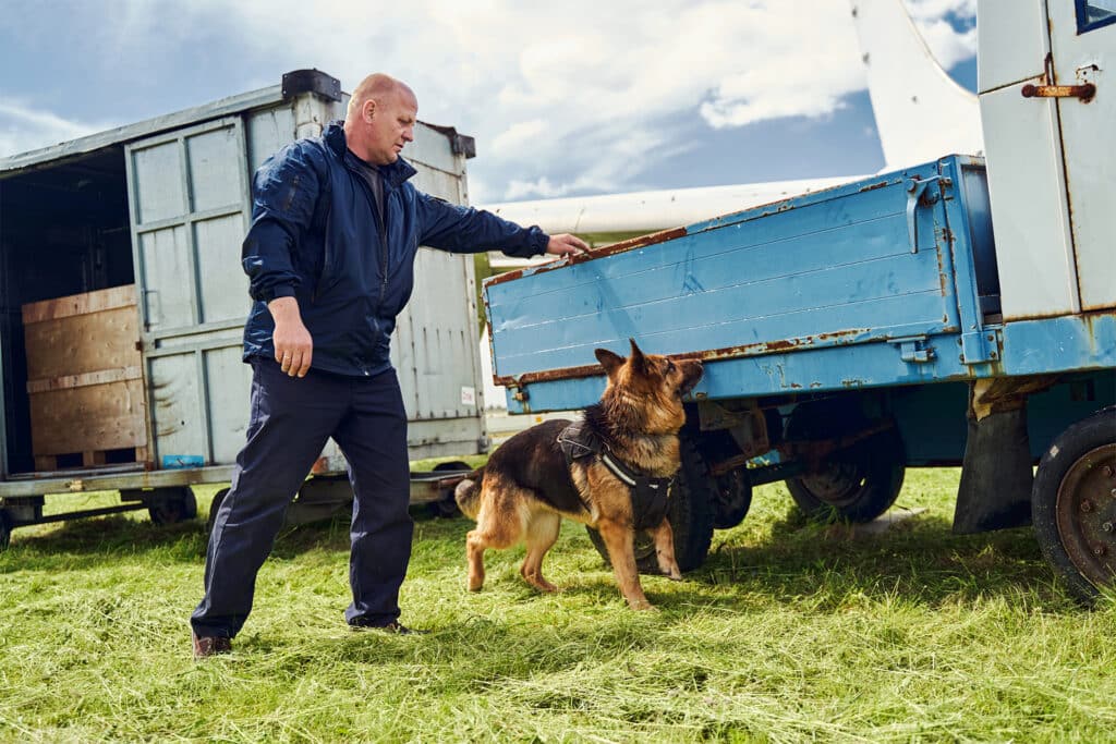 a security officer with a detector dog inspecting the area