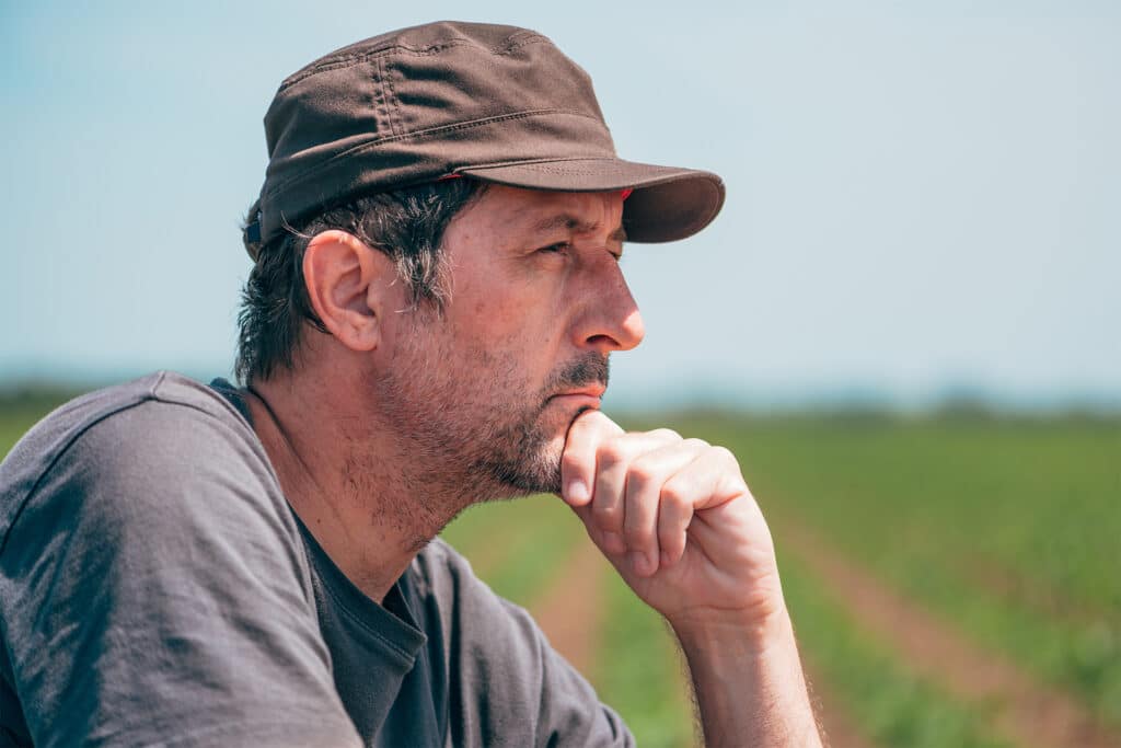 a farmer in his field thinking of how to protect the farm